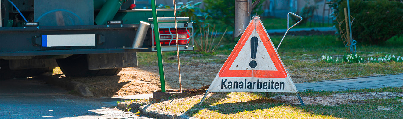 Warndreieck mit Hinweis auf Kanalarbeiten neben einem geöffneten Kanalschacht bei einer Kanalsanierung in Grömitz